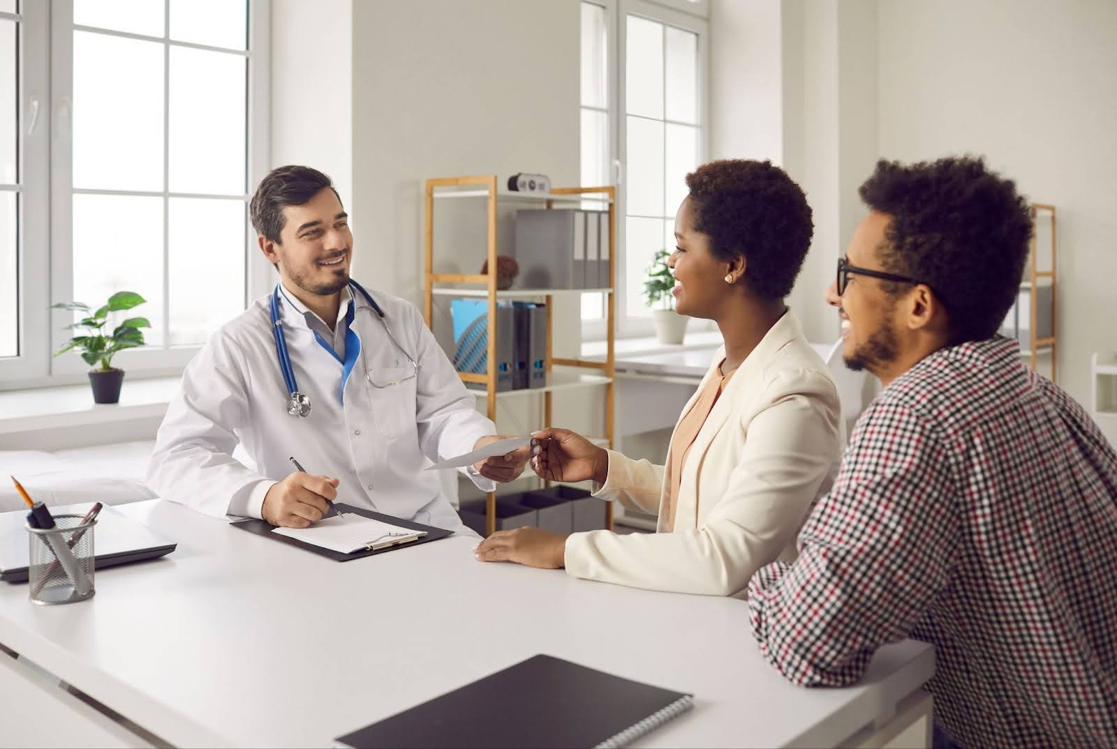 Happy married couple visiting and consulting with family doctor on whether women have prostates or not.