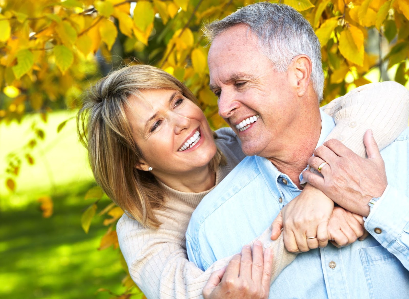 Happy older couple smile at one another while embracing.
