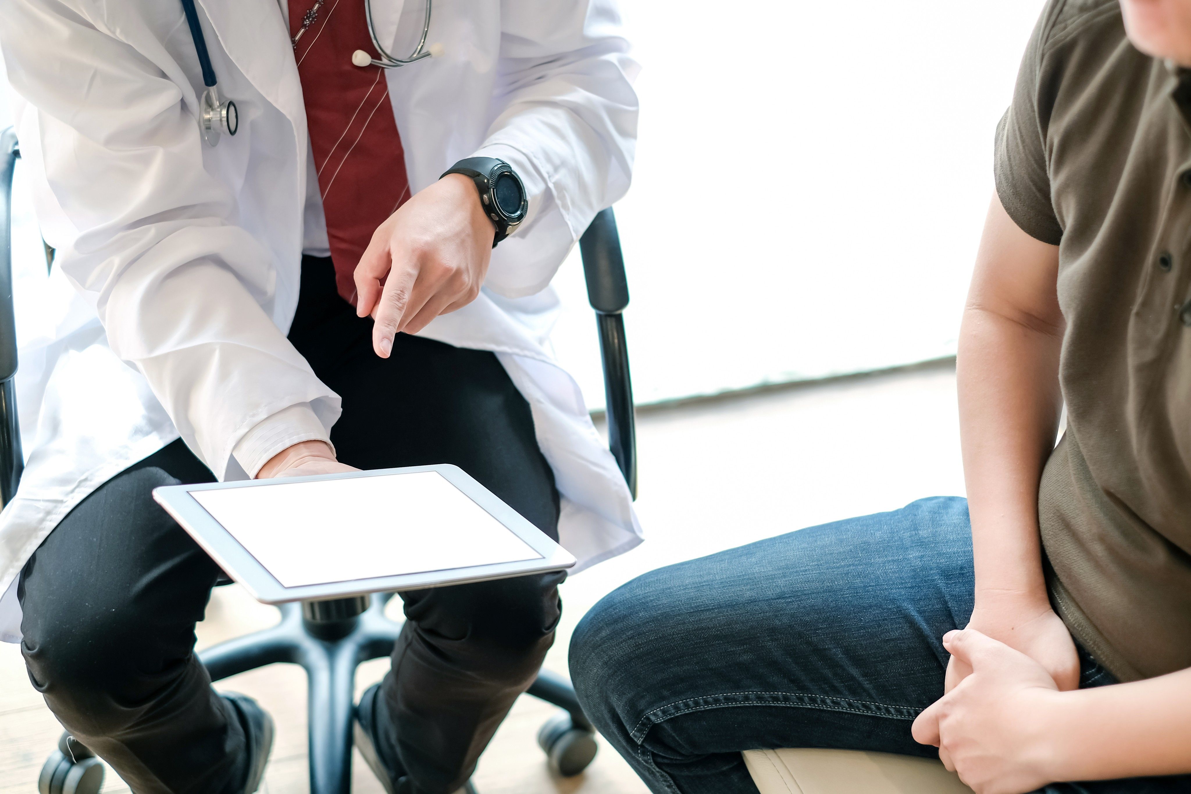 Doctor holding a tablet explaining the screening for prostate cancer process to male patient