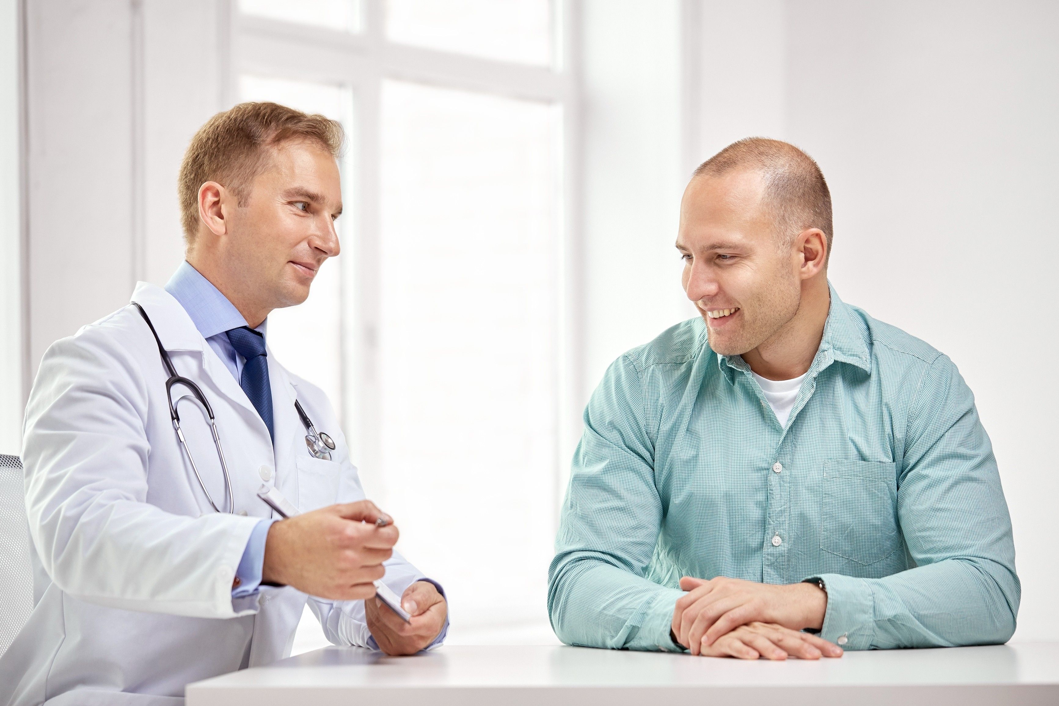 Man sitting in a doctors office talking with physician about prostate stones and his prostate health