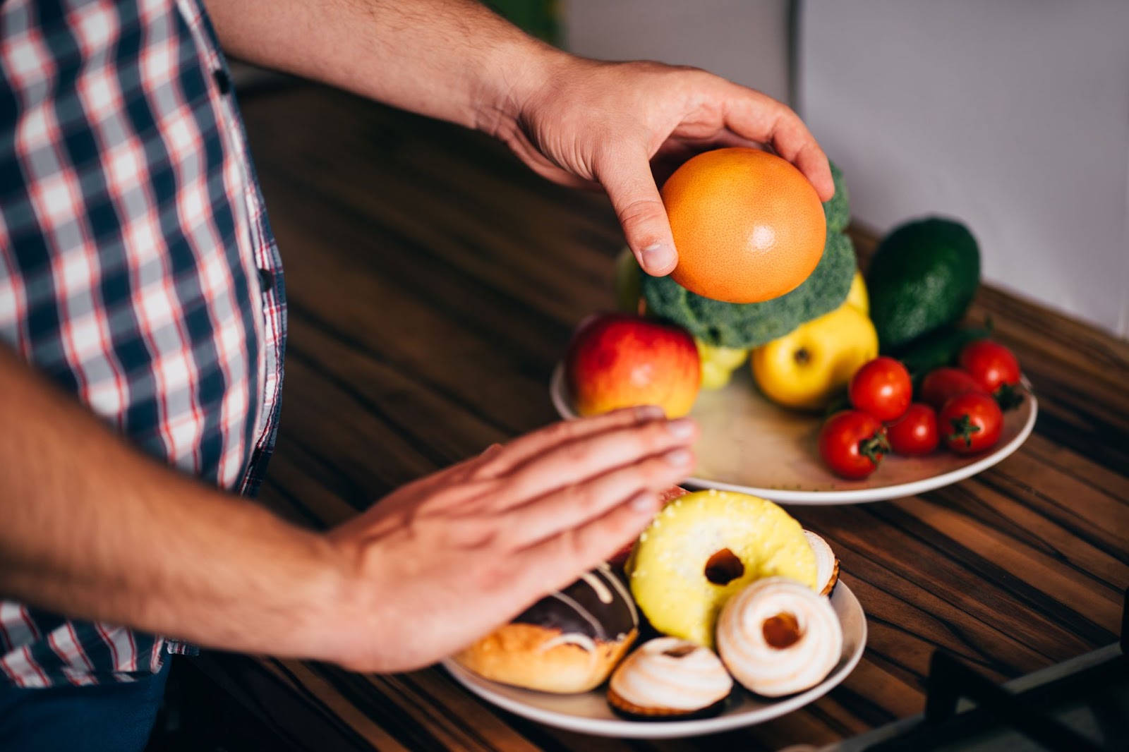 Photo of a man avoiding a plate full of donuts and choosing the plate of vegetables for healthier living and to support prostate health.