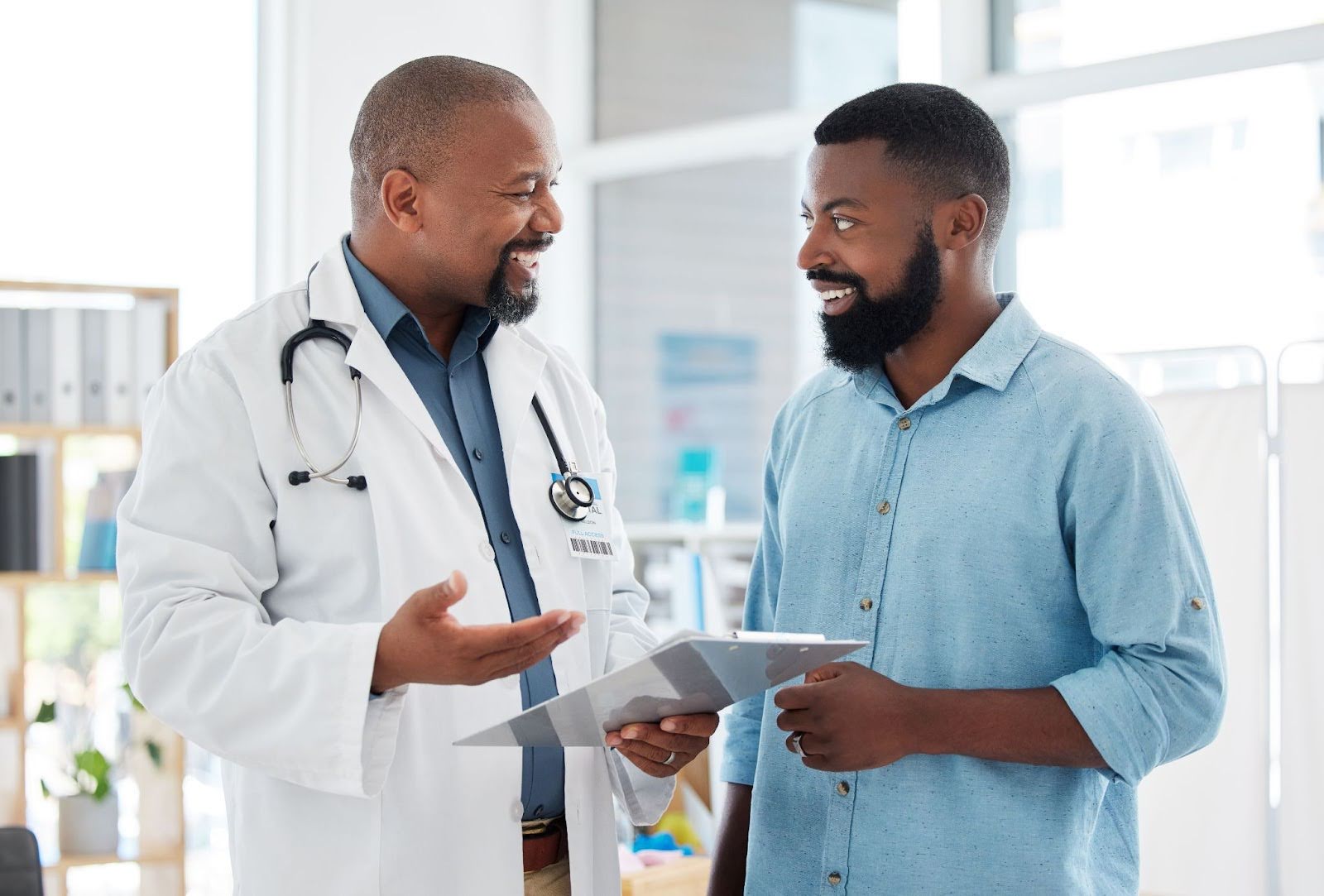 Male doctor explaining prostate artery embolization to male patient.
